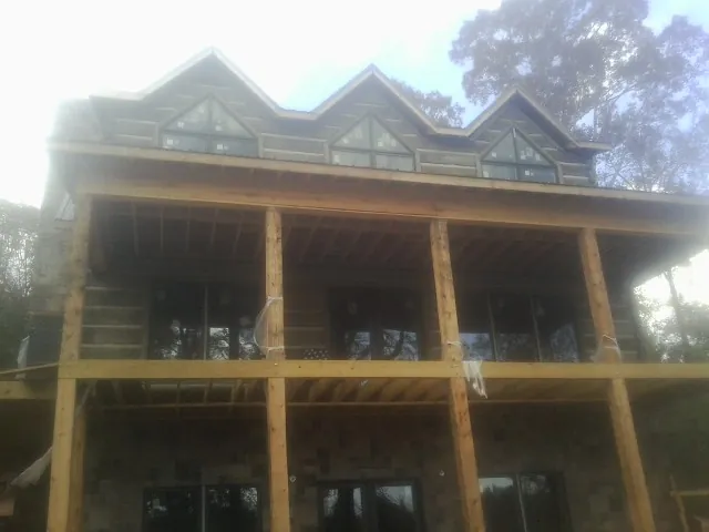 Dormers and porch framing on a large log home under construction — Roof Coating work by our crew in Swan Valley