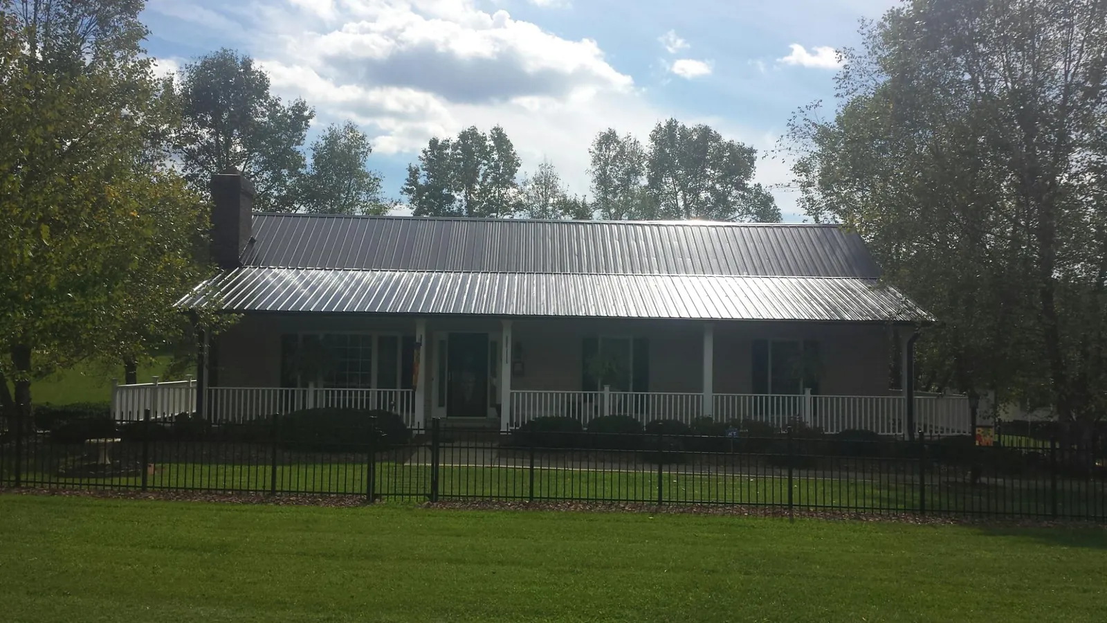 Gray metal roof on a brick ranch with a full width front porch — Gutter Guard Installation work by our crew in Swan Valley